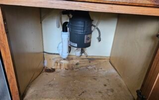 Water-damaged under-sink cabinet with garbage disposal needing repair