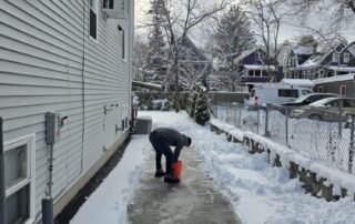 Worker applying salt after snow shoveling to keep driveway safe and clear