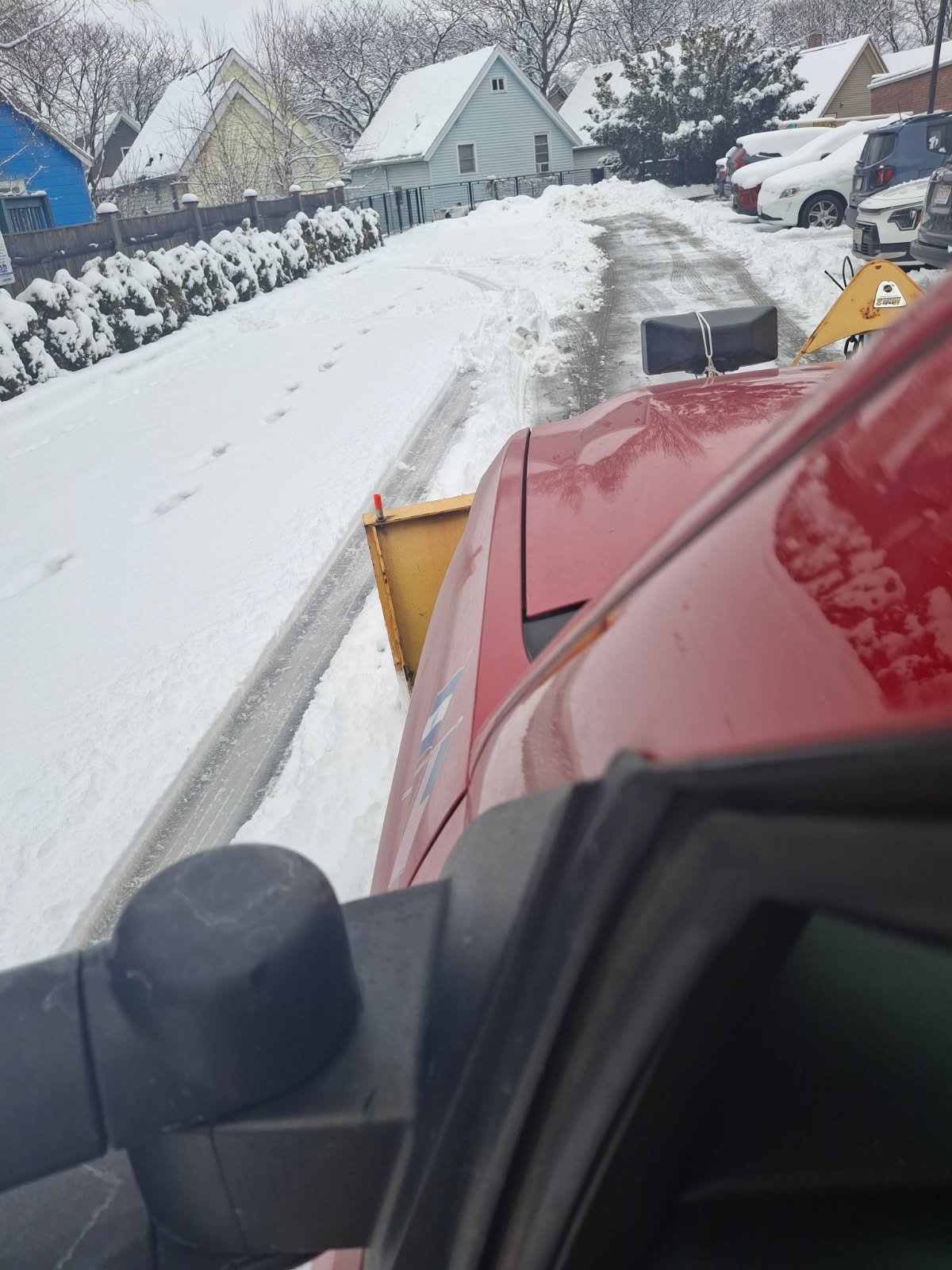 Red truck plowing snow from residential driveway for clear winter access