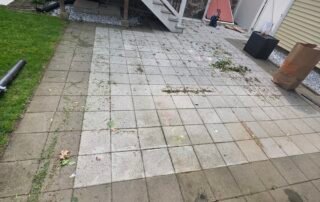 Concrete paver patio with weeds and stains before professional cleaning