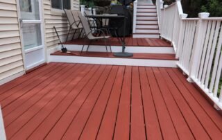 Freshly painted red deck with white railings and outdoor seating area