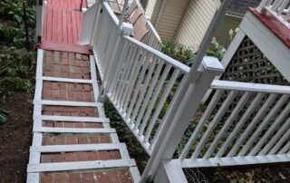 Painted red deck with white railings and brick stairway for residential home