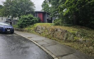 Cleared front yard with trimmed shrubs and cleaned stone retaining wall