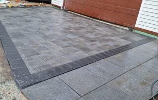 Newly installed stone paver driveway with dark border in front of garage