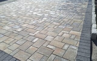 Completed stone paver driveway with dark border and professional finish