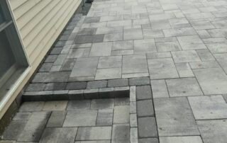 Newly installed stone paver patio with small steps and decorative edging