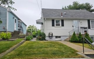 Residential front yard with trimmed grass, shrubs, and clean walkway
