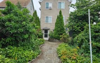 Gravel walkway with stepping stones surrounded by lush green plants and shrubs