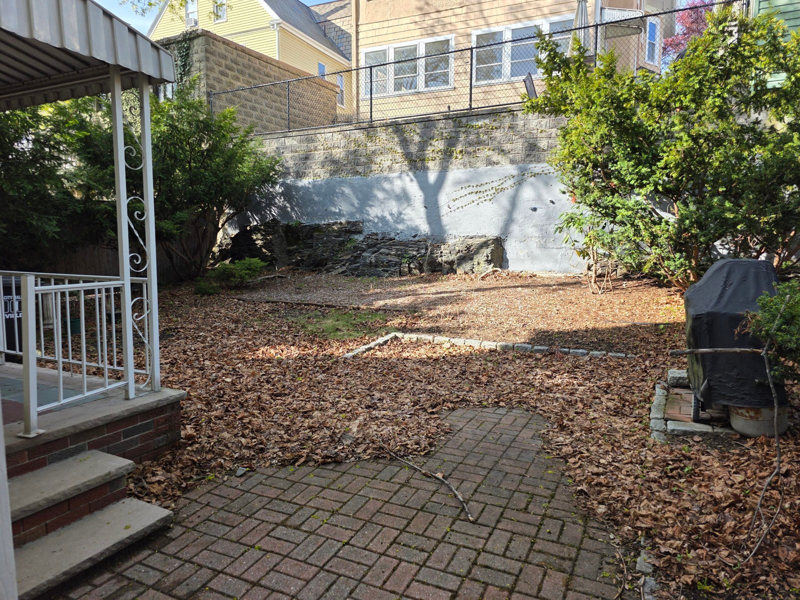 Brick patio and yard covered with leaves before professional cleanup