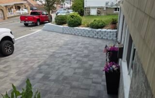 Modern stone paver driveway with retaining wall and flower planters