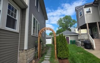 Stone walkway with wooden arbor and neatly landscaped side yard